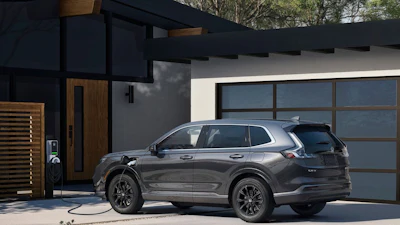 Gray Honda SUV charging at a modern home with glass garage door