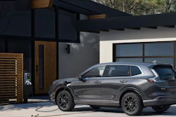 Gray Honda SUV charging at a modern home with glass garage door