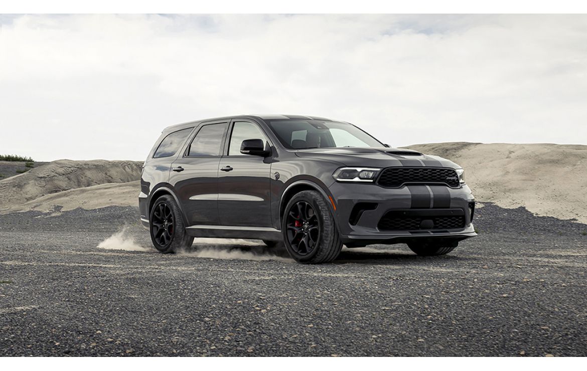 Black Dodge Durango SUV parked on rocky terrain with dusty background