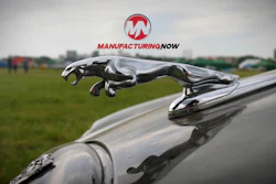 Chrome Jaguar leaping hood ornament on silver vehicle with grassy background
