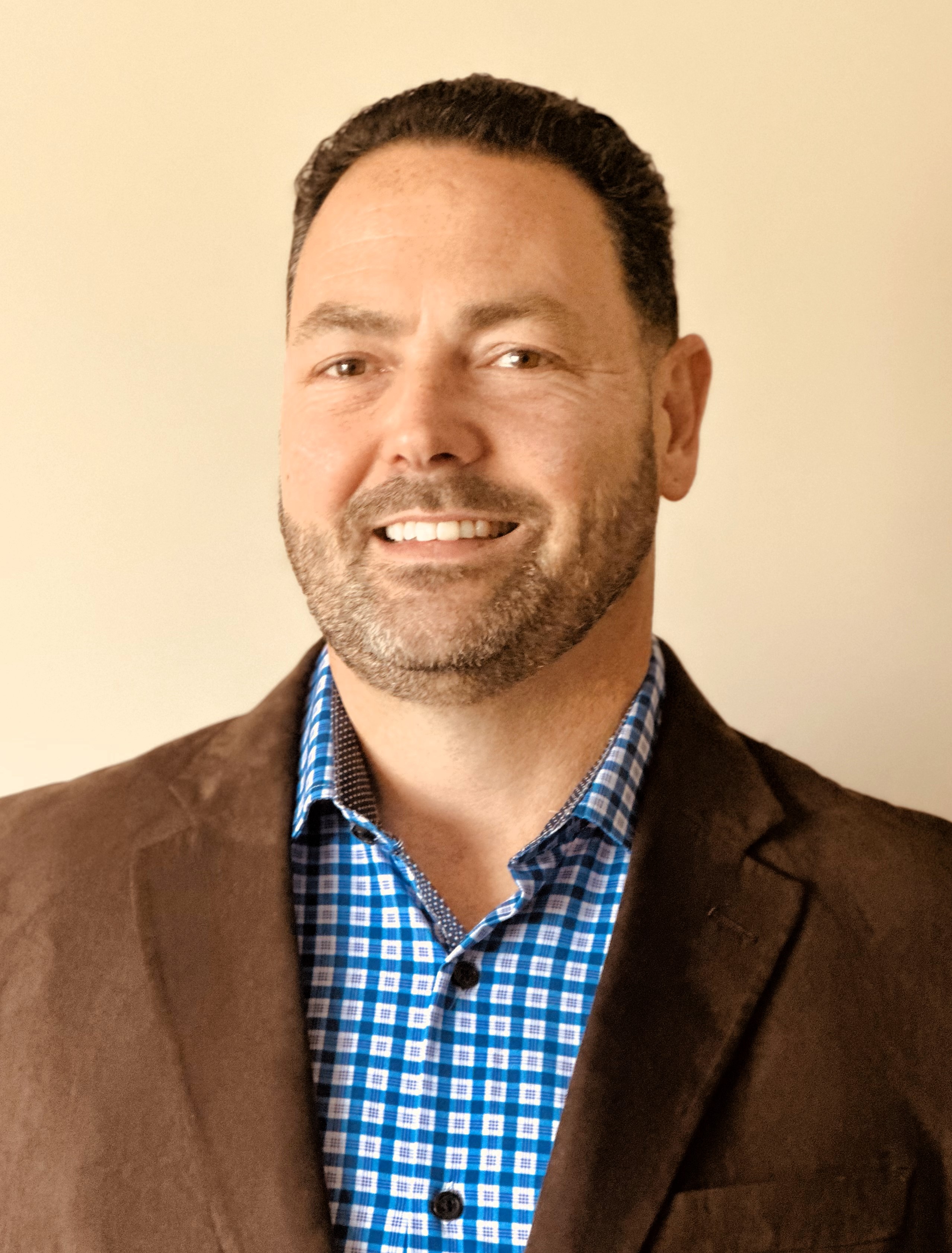 Smiling professional in brown blazer and blue checkered shirt
