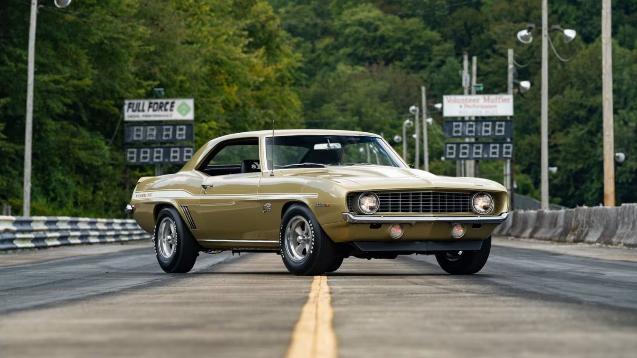 Gold vintage Chevrolet Camaro muscle car on drag racing track with timing boards