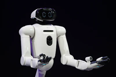 White humanoid robot with digital face and articulated arms against dark background