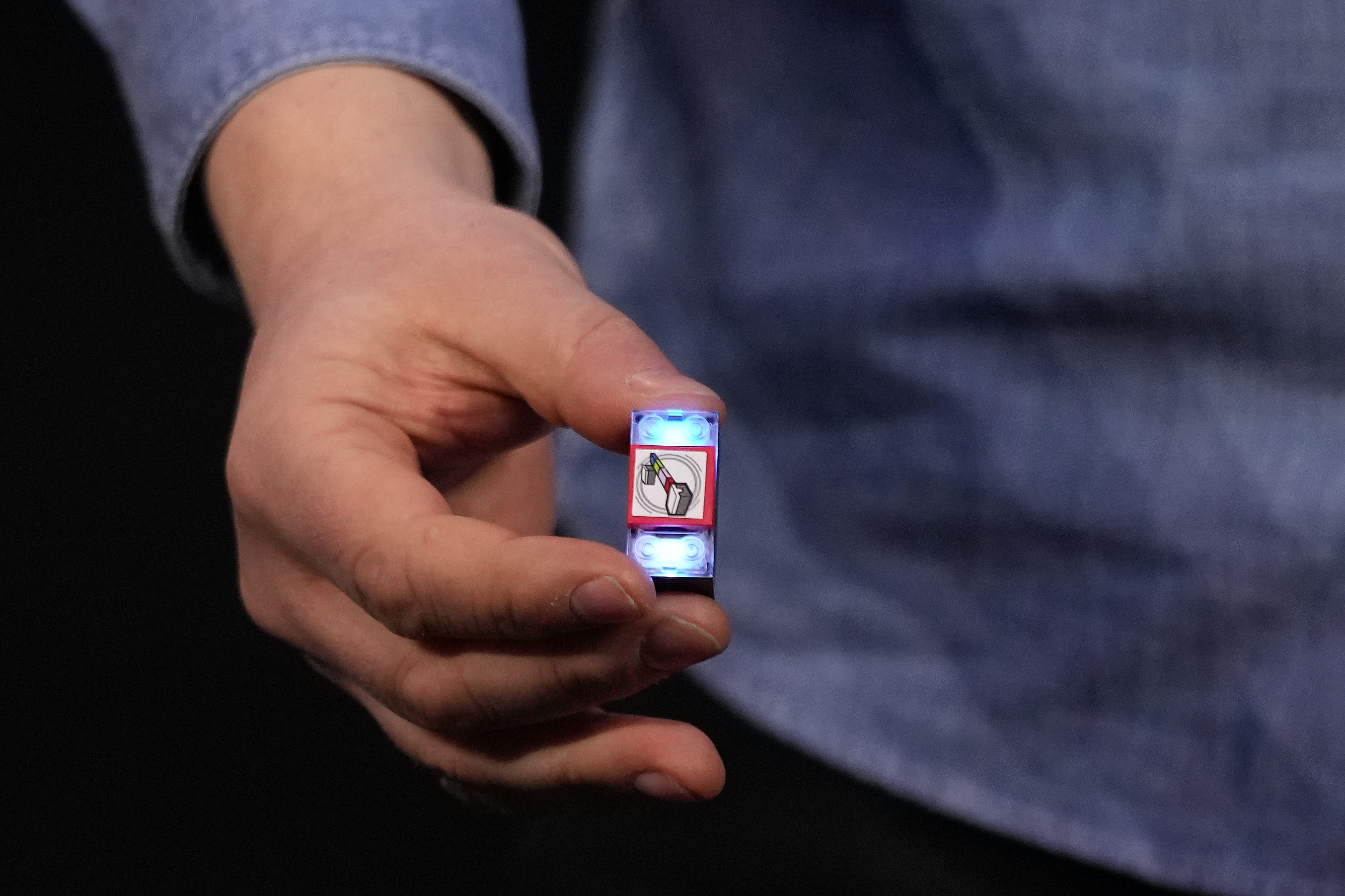 Hand holding small electronic device with colorful digital display