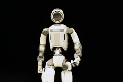 White humanoid robot with articulated limbs standing against black background