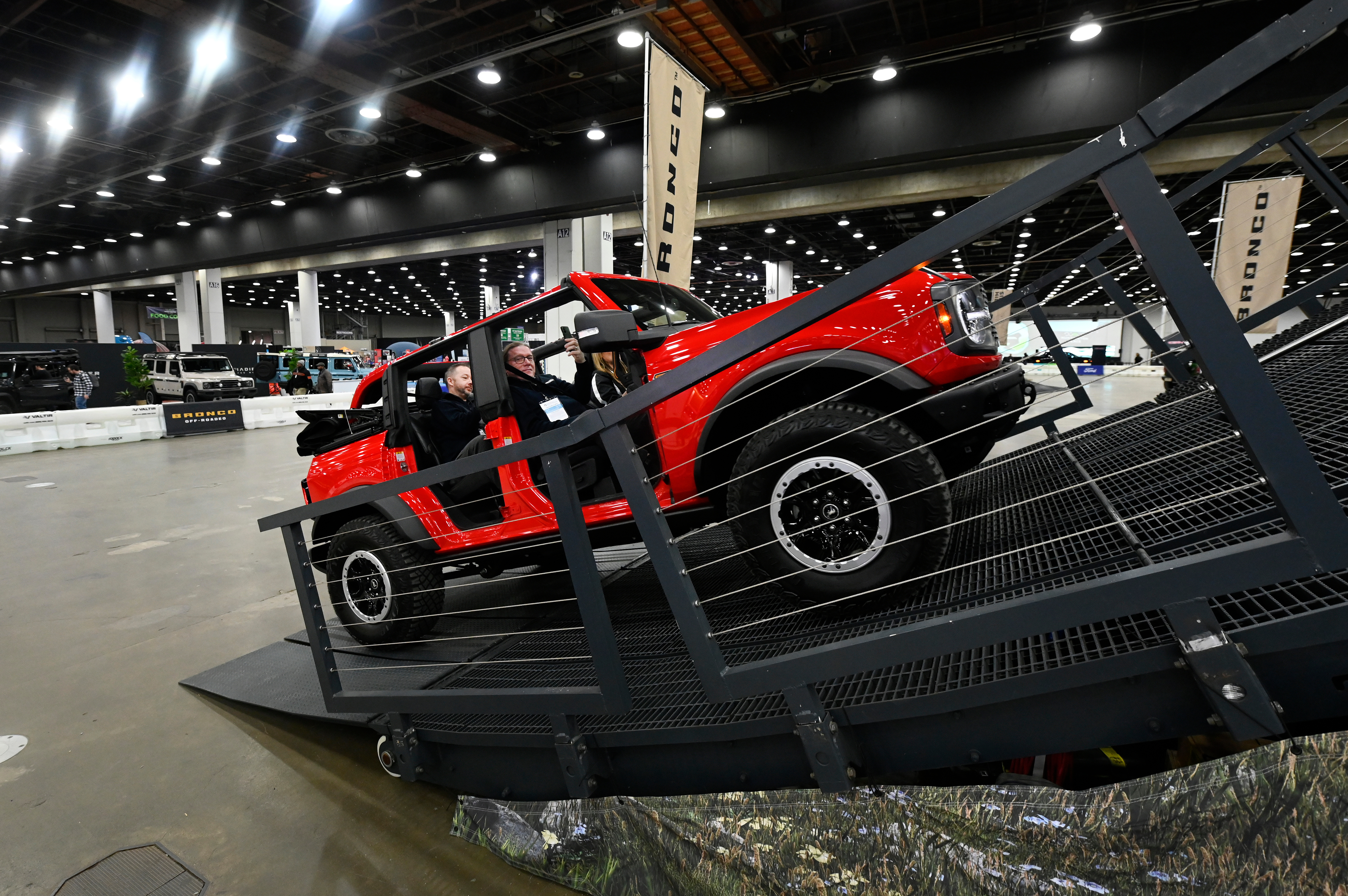 Red off-road vehicle tilted on metal display platform at automotive show