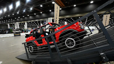 Red off-road vehicle tilted on metal display platform at automotive show