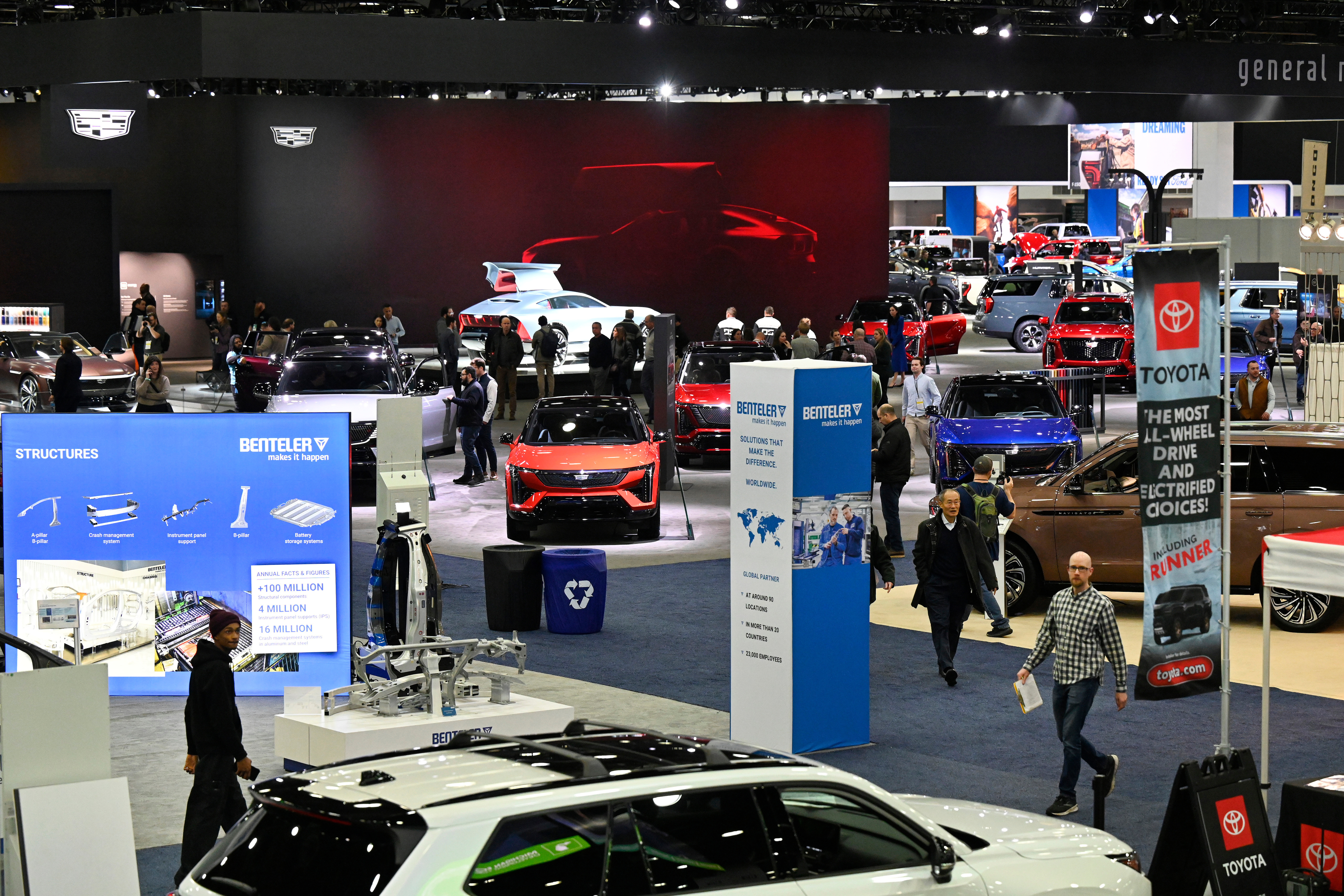 Bustling auto show floor with vehicles, displays, and attendees exploring automotive exhibits
