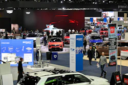 Bustling auto show floor with vehicles, displays, and attendees exploring automotive exhibits
