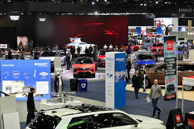 Bustling auto show floor with vehicles, displays, and attendees exploring automotive exhibits