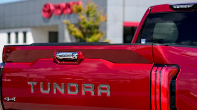 Red Toyota Tundra pickup truck with 4x4 badge, parked near a building