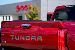 Red Toyota Tundra pickup truck with 4x4 badge, parked near a building