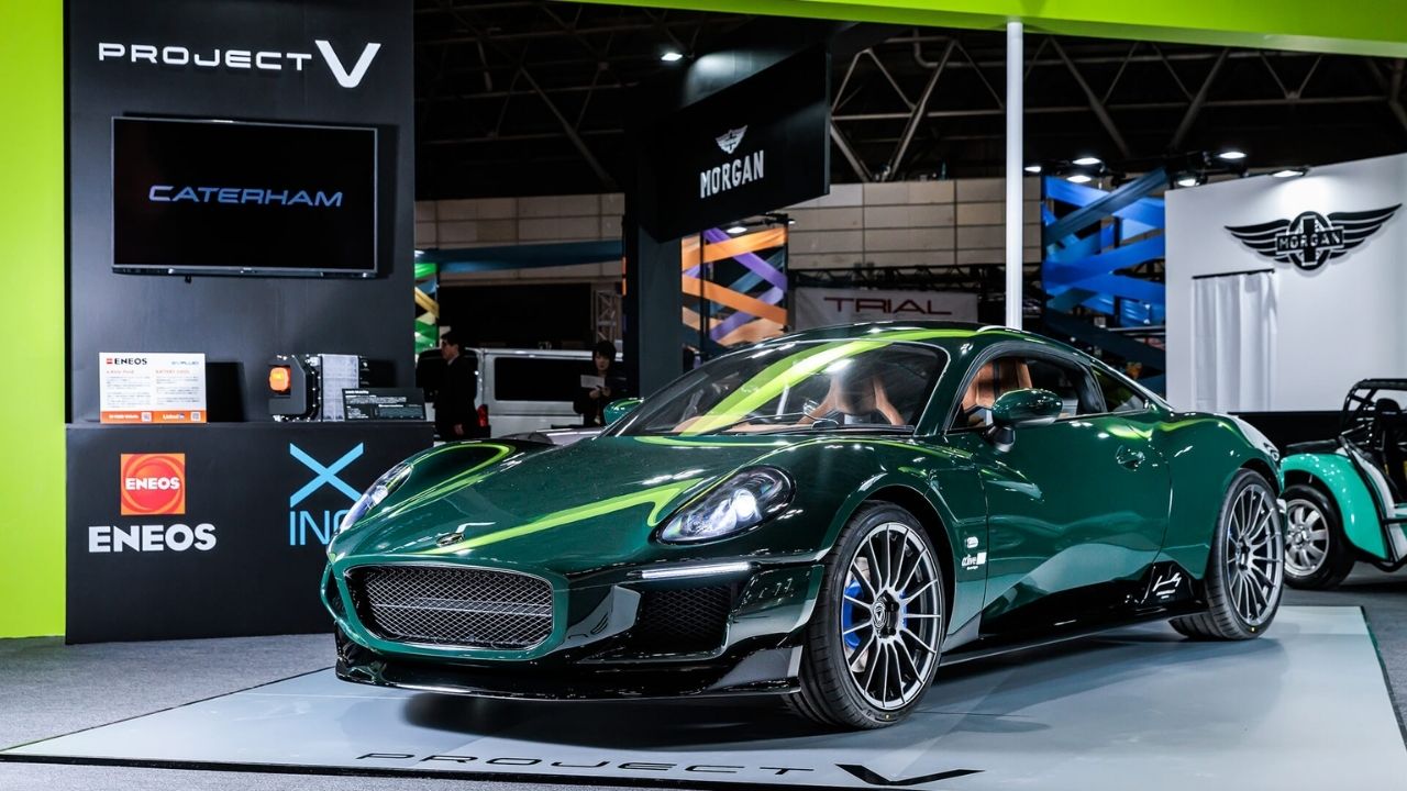 Dark green Caterham sports car displayed at automotive exhibition with sponsor logos