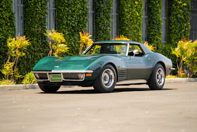 Classic green 1970s Chevrolet Corvette Stingray parked near ivy-covered wall