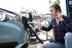 Person charging an electric vehicle at a charging station