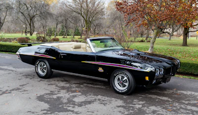 Vintage black Pontiac GTO convertible parked in autumn park setting