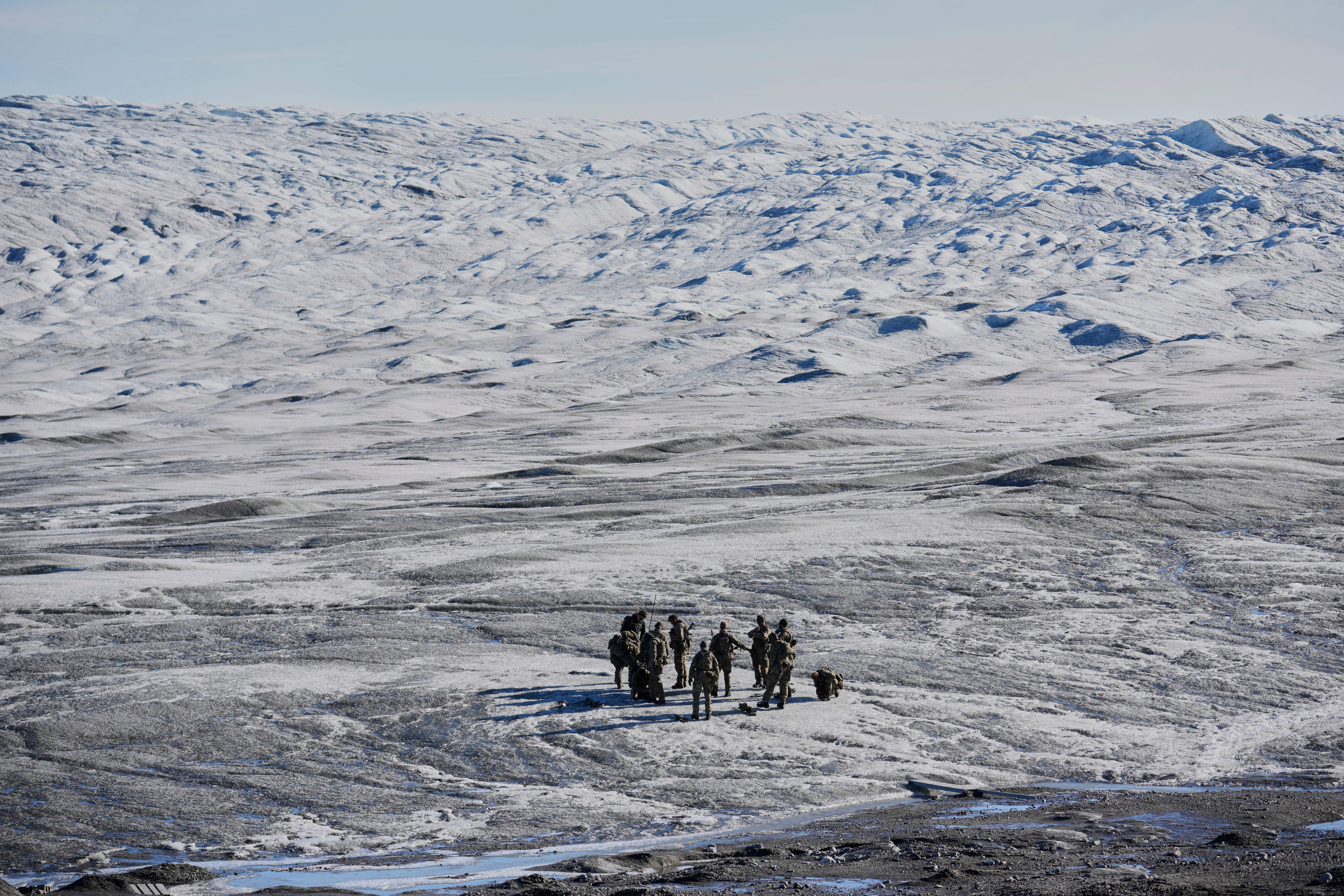 Small group of people walking across a vast, icy Arctic or Antarctic landscape