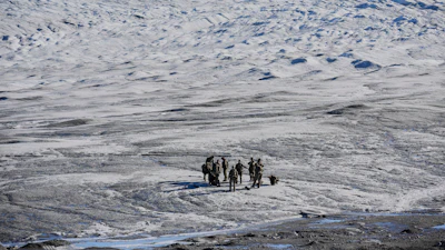 Small group of people walking across a vast, icy Arctic or Antarctic landscape