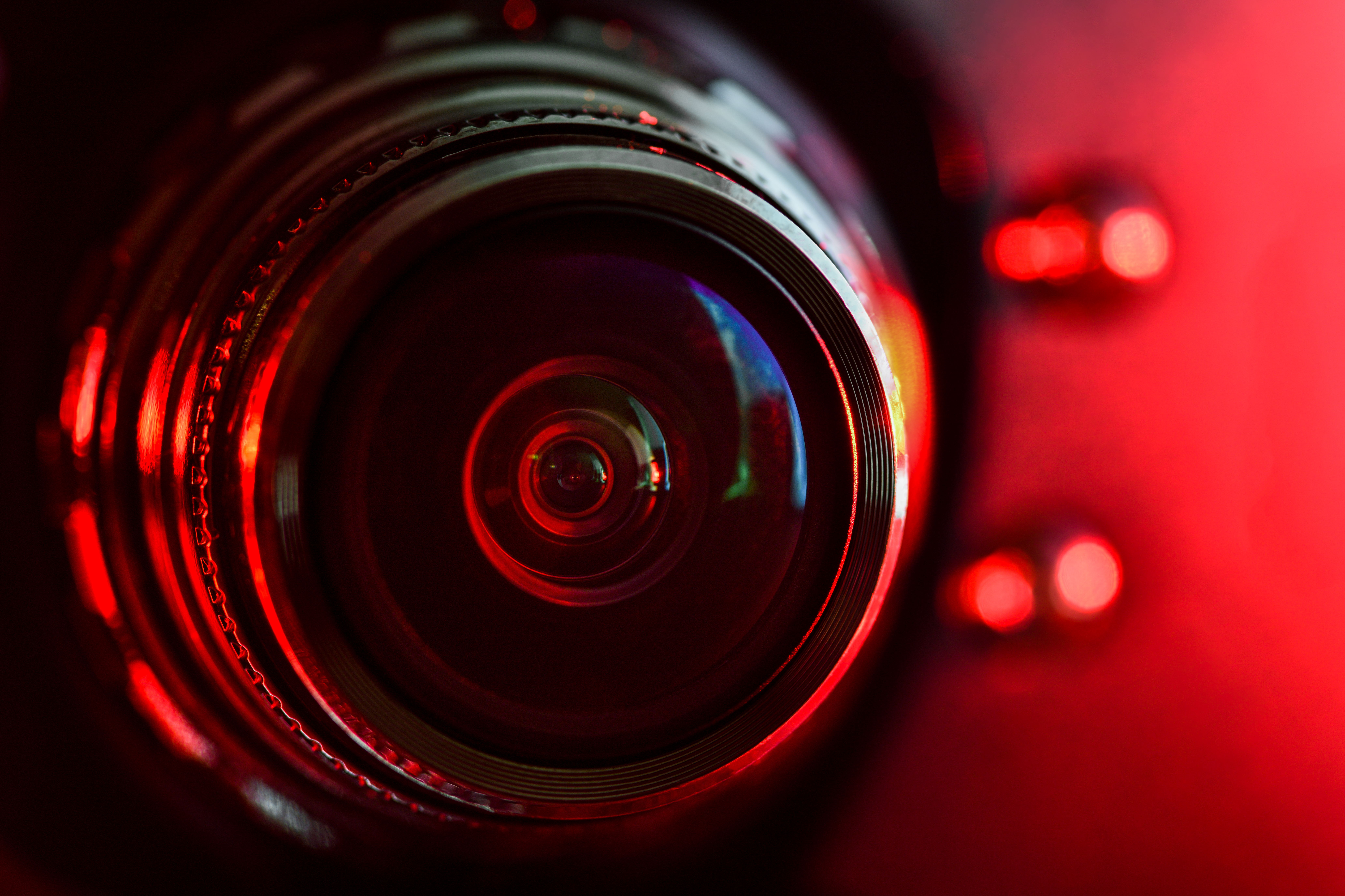 Camera lens close-up with red dramatic lighting and circular reflections