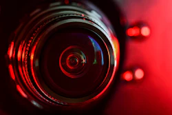 Camera lens close-up with red dramatic lighting and circular reflections