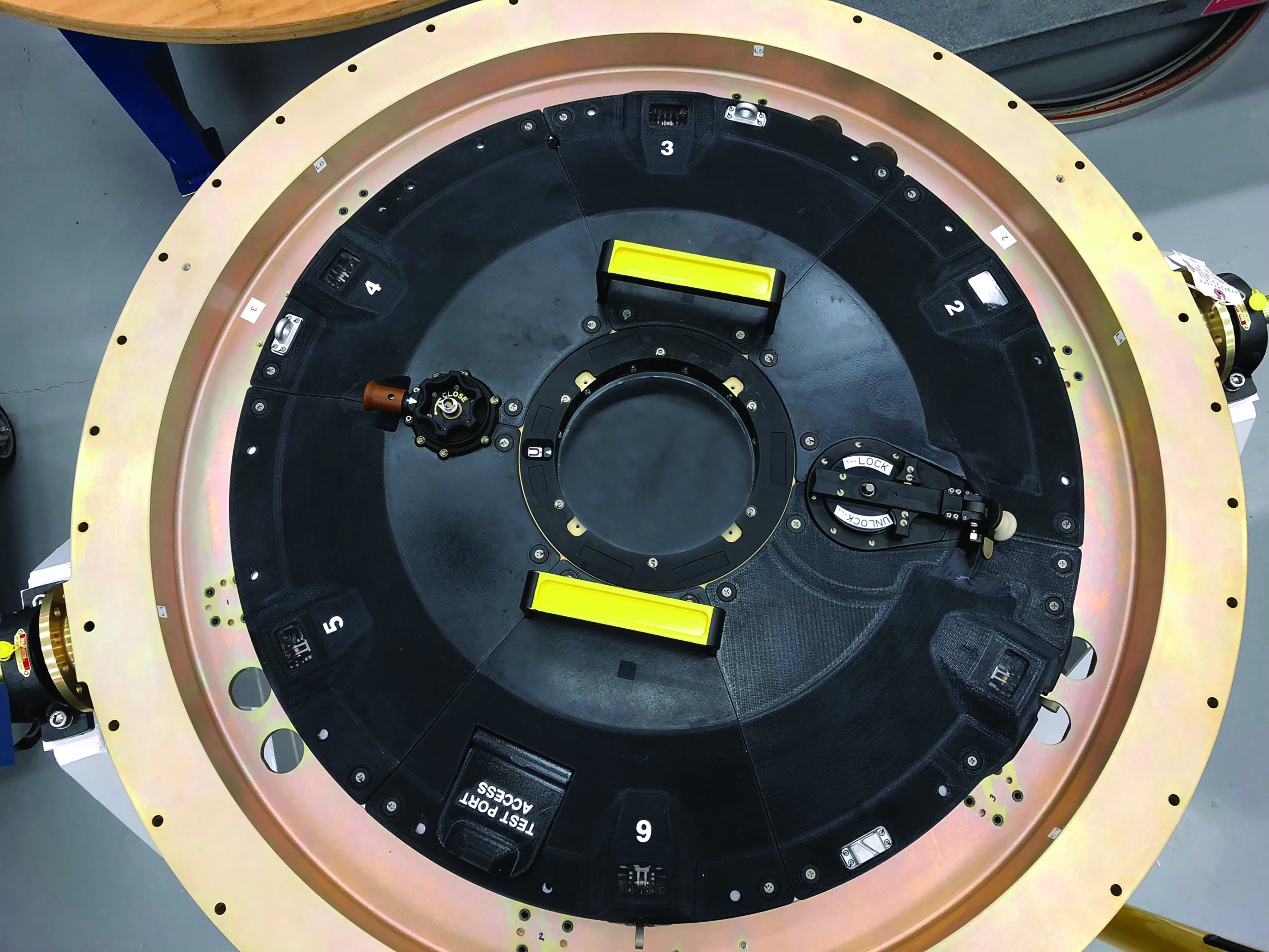 Circular mechanical device with black surface, numbered sections, and yellow markers
