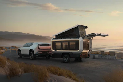 White electric SUV with pop-up camper trailer parked on beach at misty dawn