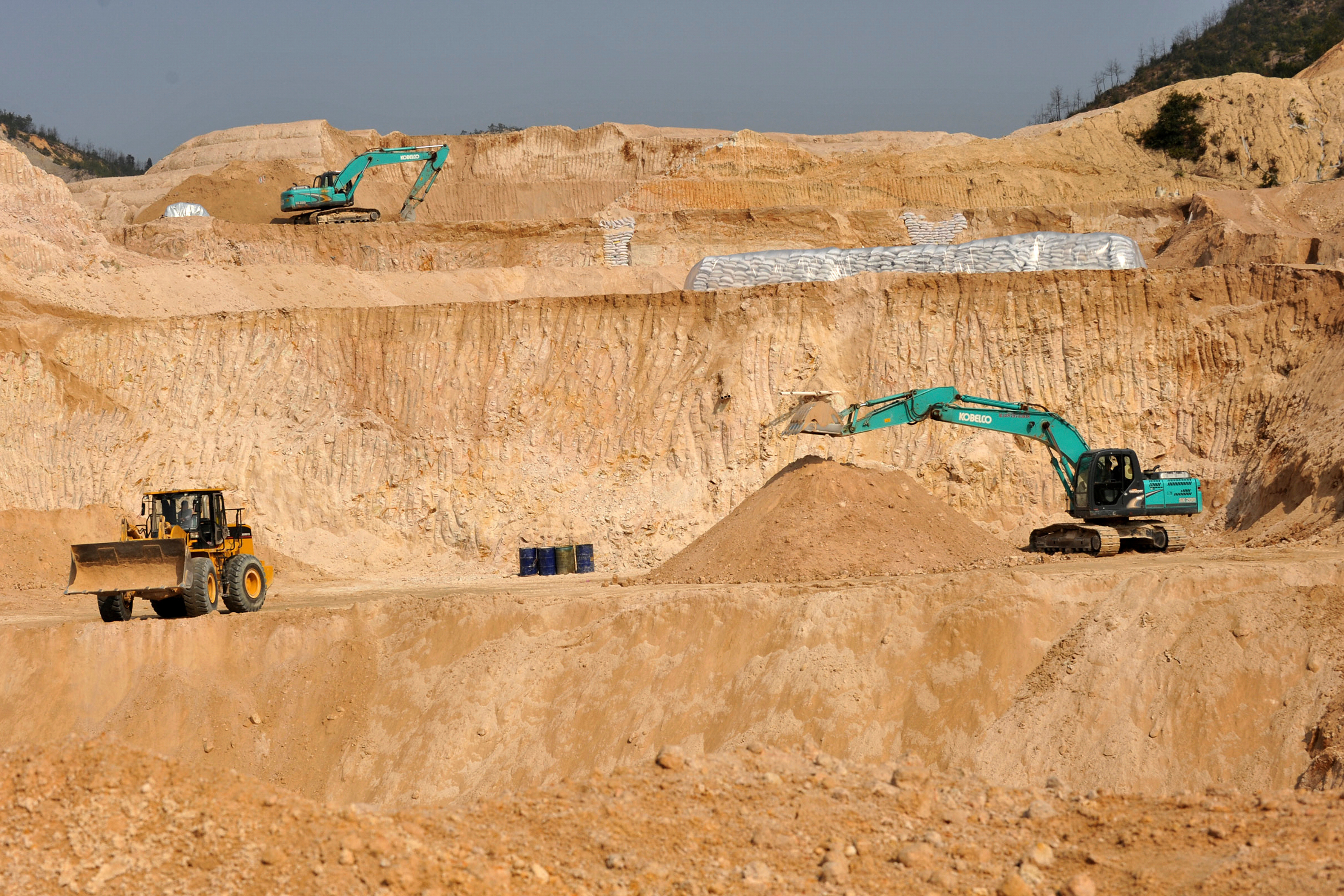 Construction site with excavators and wheel loader in sandy quarry landscape