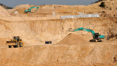 Construction site with excavators and wheel loader in sandy quarry landscape