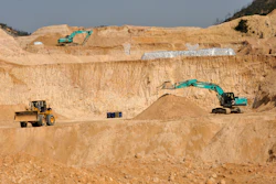 Construction site with excavators and wheel loader in sandy quarry landscape