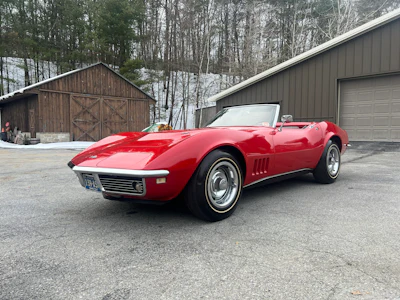 Classic red Chevrolet Corvette convertible parked in snowy winter setting