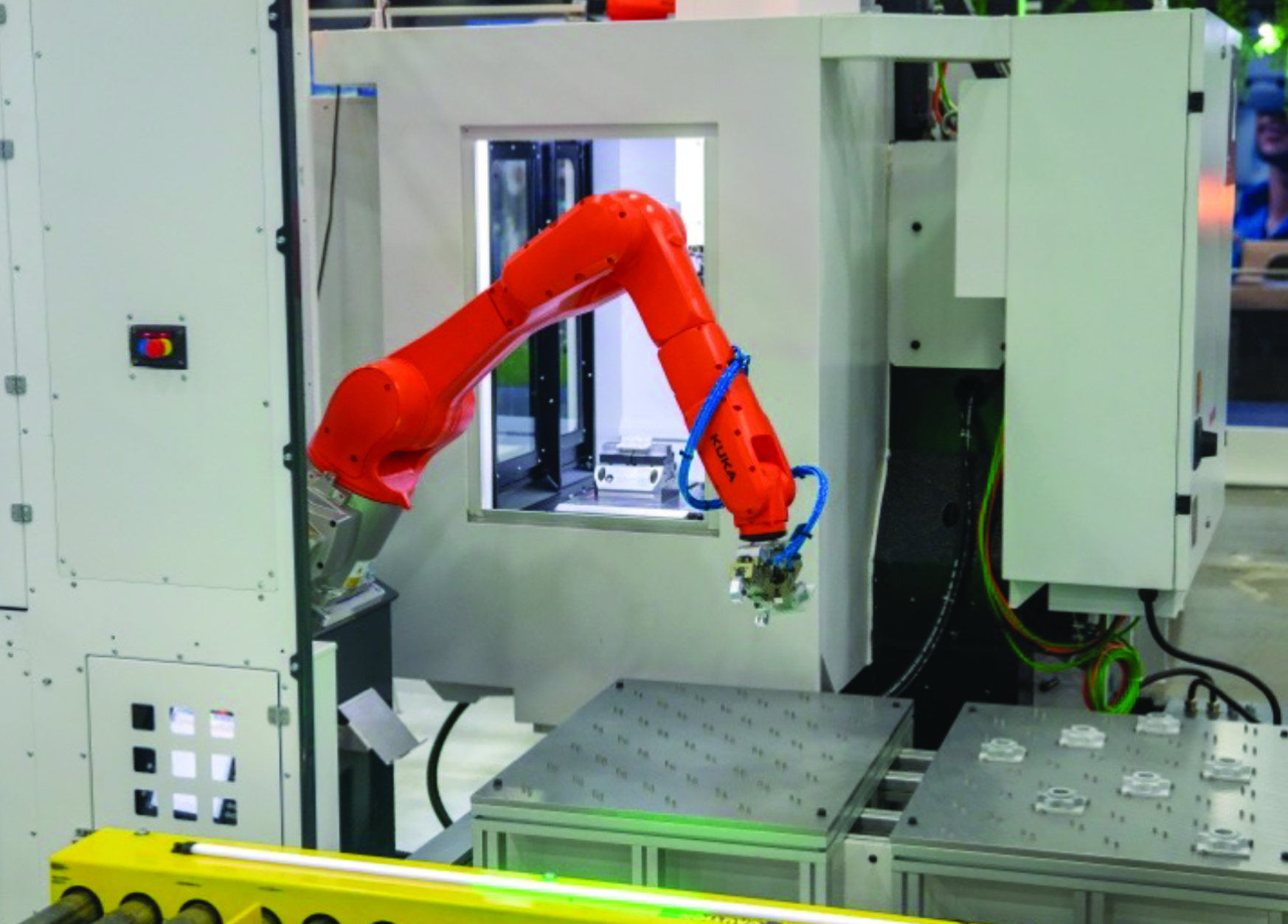 Orange industrial robotic arm performing precision manufacturing task