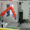 Orange industrial robotic arm performing precision manufacturing task