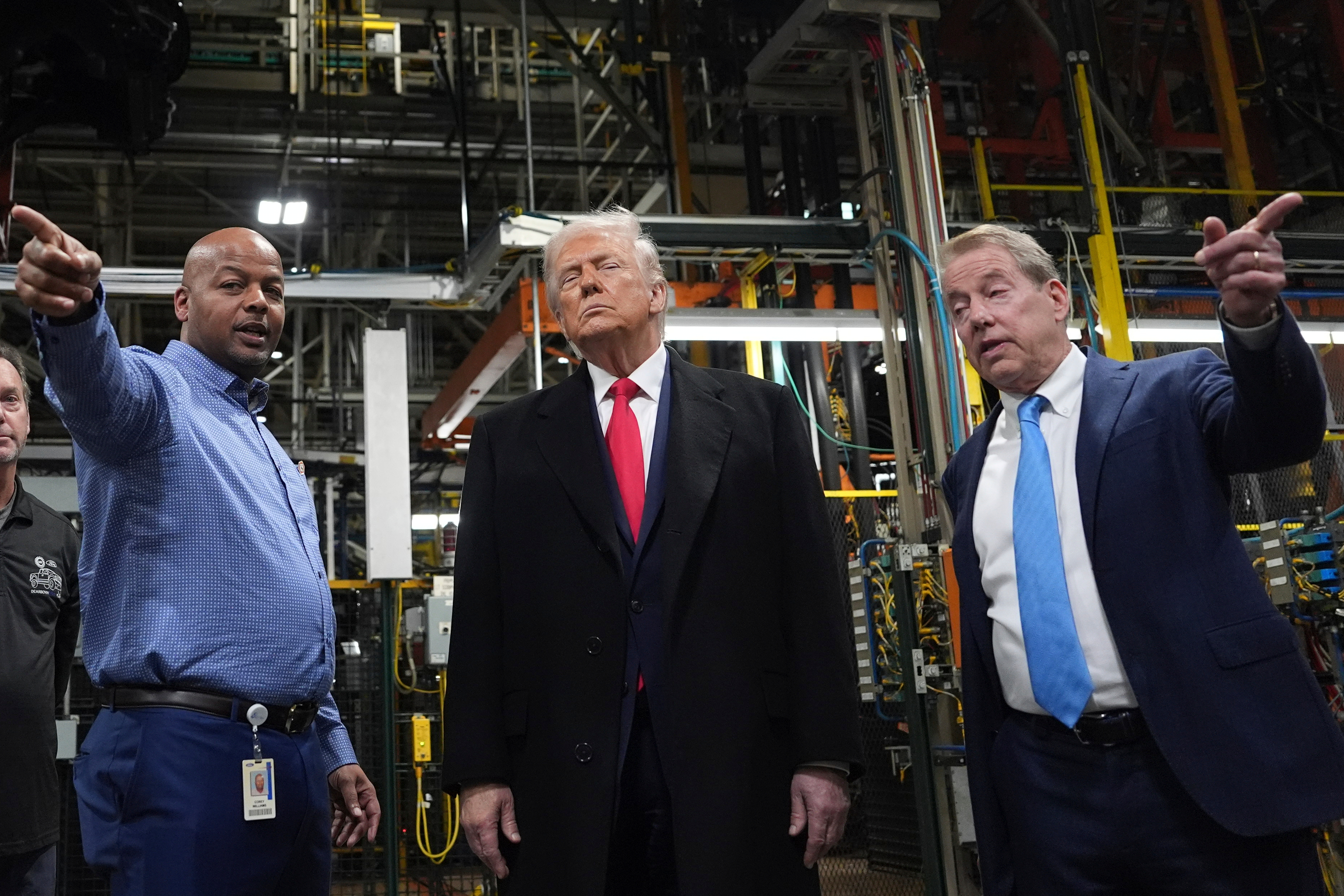 Three men standing in an industrial manufacturing facility with machinery in background