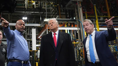 Three men standing in an industrial manufacturing facility with machinery in background