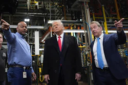 Three men standing in an industrial manufacturing facility with machinery in background