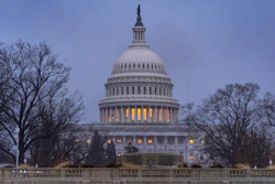 U.S. Capitol Building illuminated at dusk with bare winter trees and classical dome architecture
