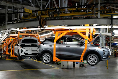 Electric vehicle on orange assembly line equipment in automotive manufacturing facility