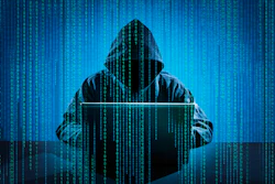 Hooded figure using laptop with digital binary code background