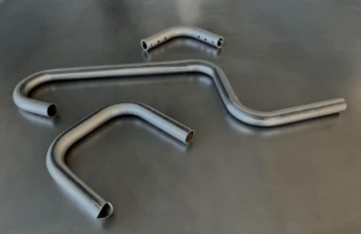 Curved metal pipes or exhaust system components on gray surface