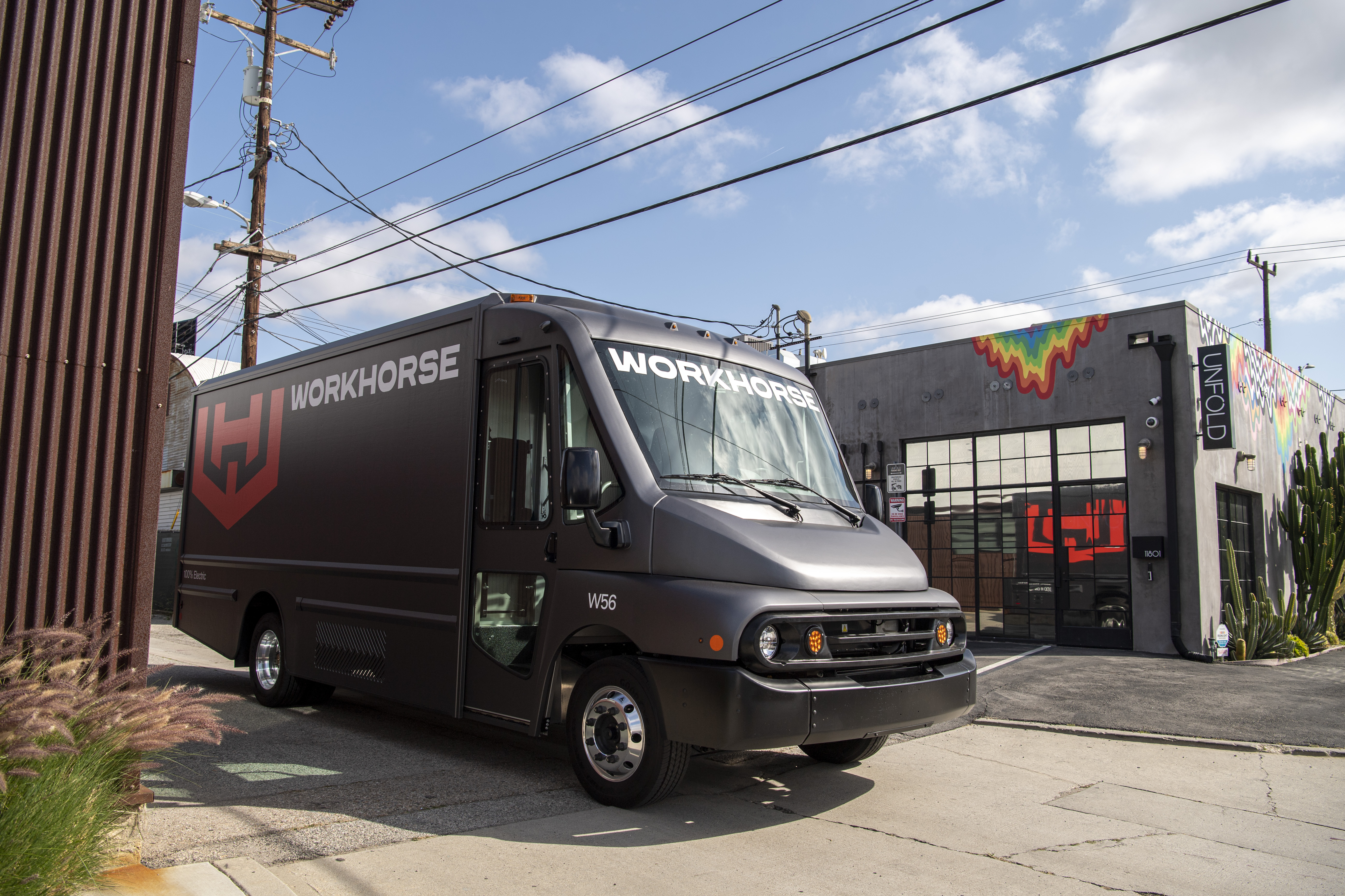 Black Workhorse delivery truck parked in front of modern facility with colorful rainbow logo accent on building