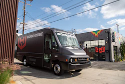 Black Workhorse delivery truck parked in front of modern facility with colorful rainbow logo accent on building