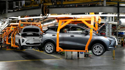 Electric vehicle assembly on orange robotic fixture in automotive manufacturing plant