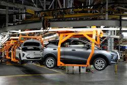 Electric vehicle assembly on orange robotic fixture in automotive manufacturing plant