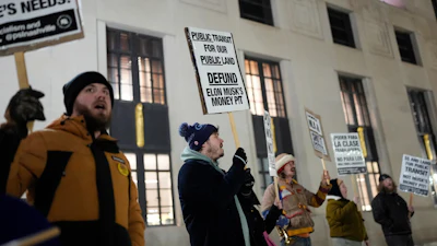 Protesters holding signs advocating for public transit funding and against Elon Musk's involvement in transit projects