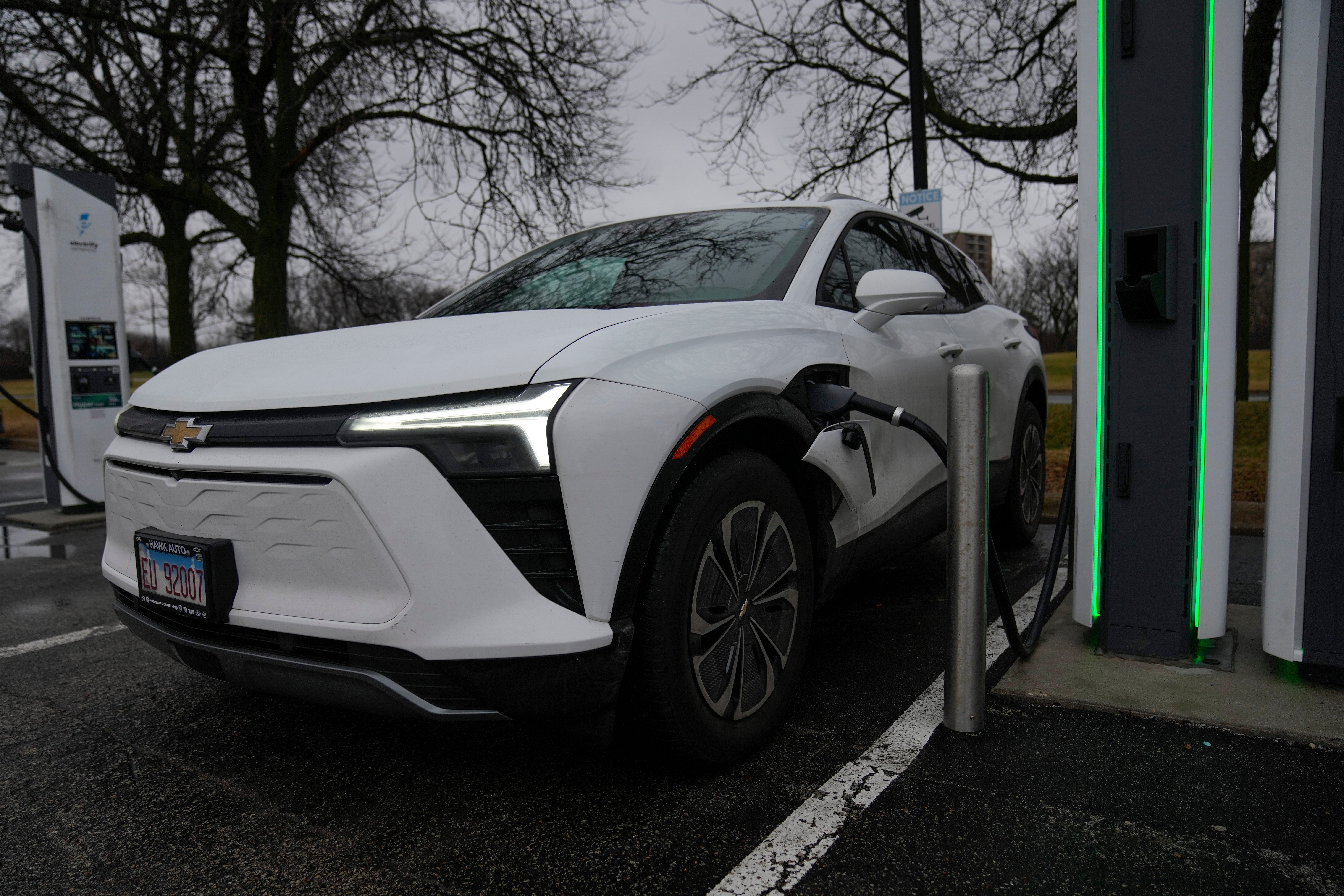 White Chevrolet Bolt EV charging at public electric vehicle charging station with green accents