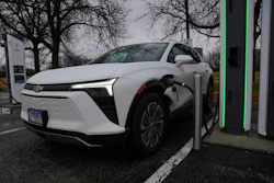 White Chevrolet Bolt EV charging at public electric vehicle charging station with green accents