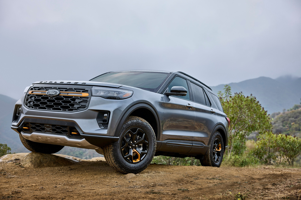 Silver Kia Niro EV SUV parked on dirt terrain with mountains and vegetation in background