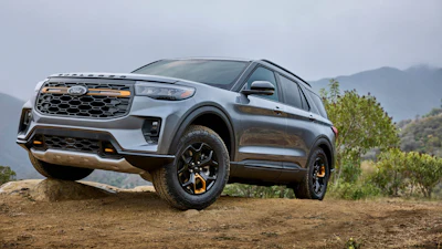 Silver Kia Niro EV SUV parked on dirt terrain with mountains and vegetation in background