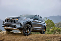 Silver Kia Niro EV SUV parked on dirt terrain with mountains and vegetation in background