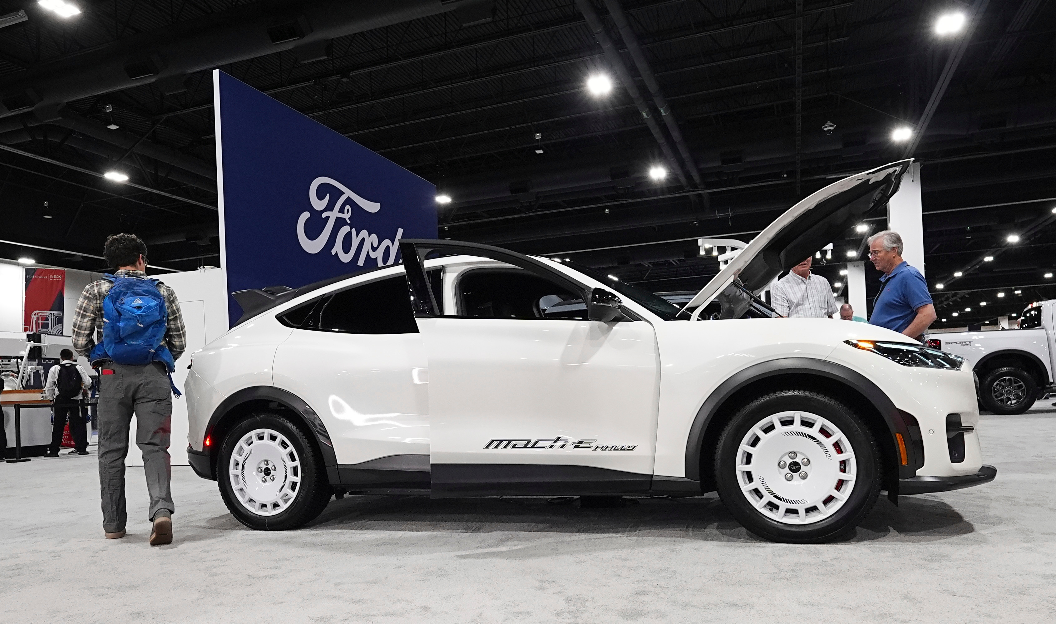 White Mazda MX-5 Miata sports car on display at automotive show with Ford signage visible